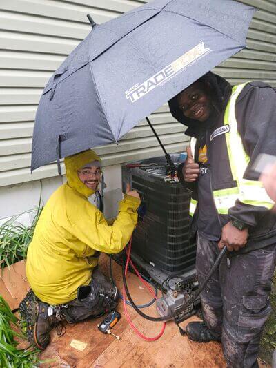 first call heating volunteers working in the rain on a furnace donation installation