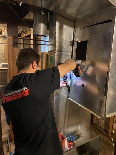 first call heating volunteer installing a furnace panel during the warm hearts donation