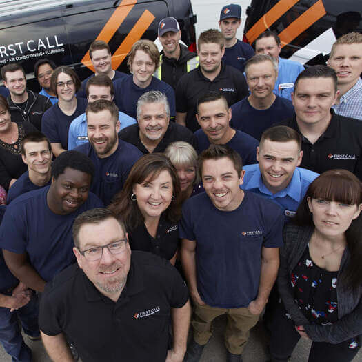 First Call Heating & Air Conditioning team gathered together outside company vehicles